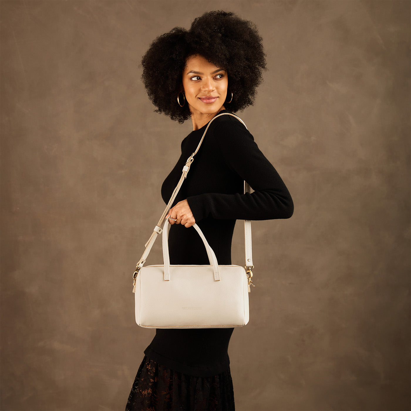 Pebbled Bone*Oversized | Model holding mini duffle shaped handbag with crossbody strap