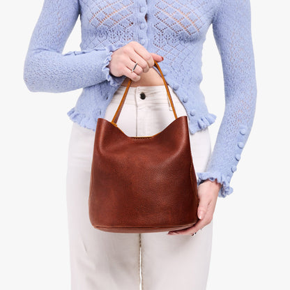 Nutmeg*Large | Model holding symmetrical bucket bag with handle, latch closure, and removable crossbody strap