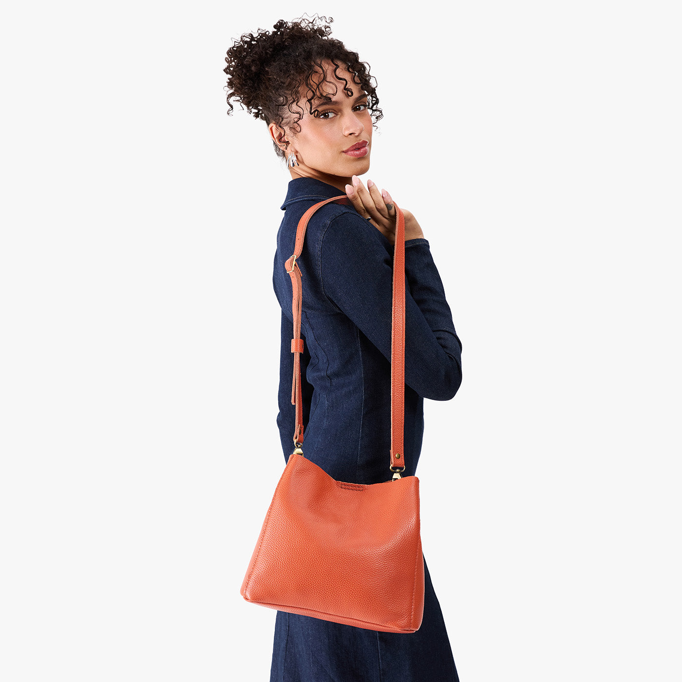 Koi | Model wearing symmetrical bucket bag with latch closure and removable crossbody strap