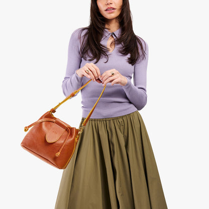 Sienna*Small | Model holding symmetrical leather bag with leather drawstring closure and adjustable shoulder strap
