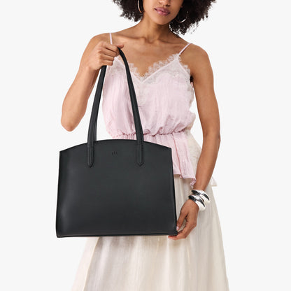 Black*Large | Model carrying leather tote bag with handles, adjustable crossbody strap, and two back pockets
