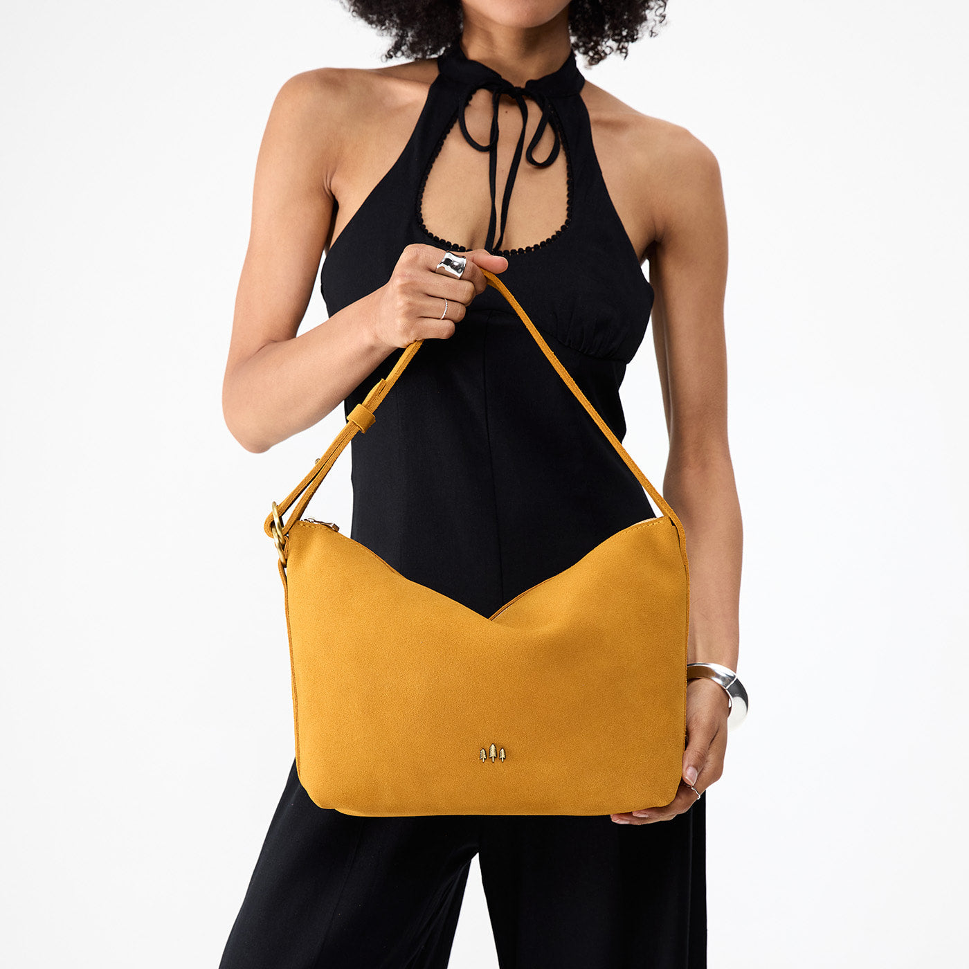 Dijon*Large | Model holding a Slouchy Shoulder Bag that has a zipper opening and three metal tree emblems