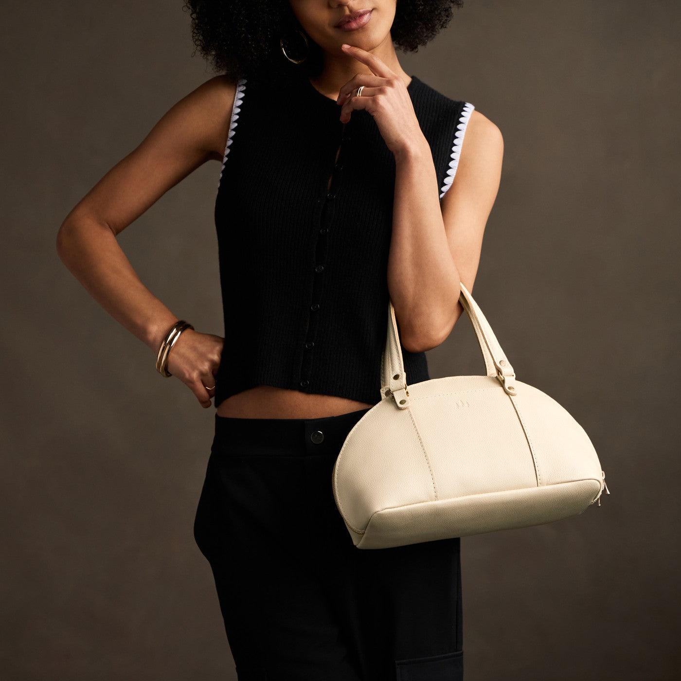 Pebbled Bone*Small | Model holding a half circle crossbody bag with handles and removable crossbody strap