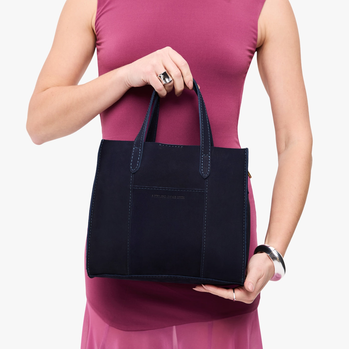 Velvet Blue | Model holding structured mid-size tote bag with overlapping panels and crossbody strap