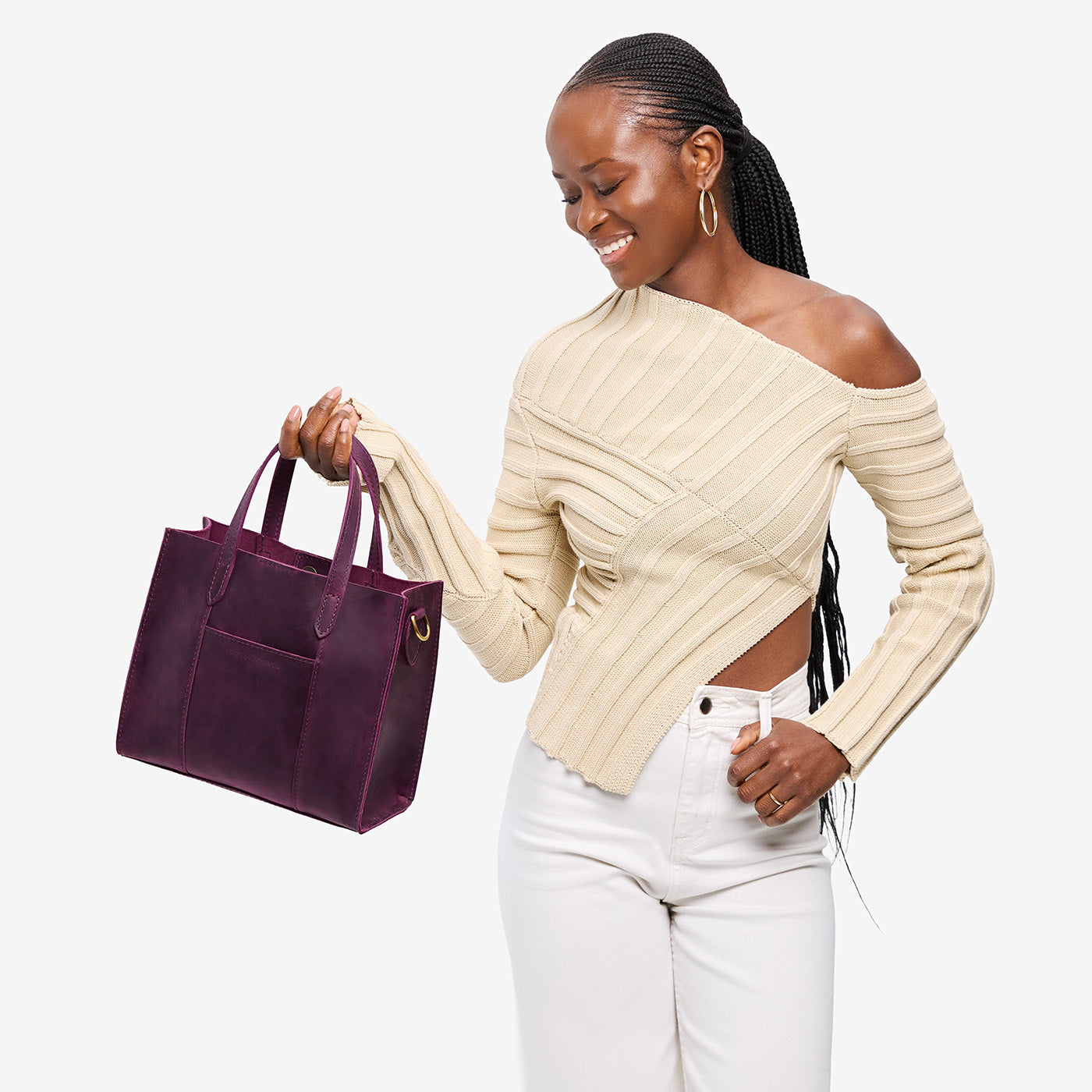 Larkspur | Model holding structured mid-size tote bag with overlapping panels and crossbody strap
