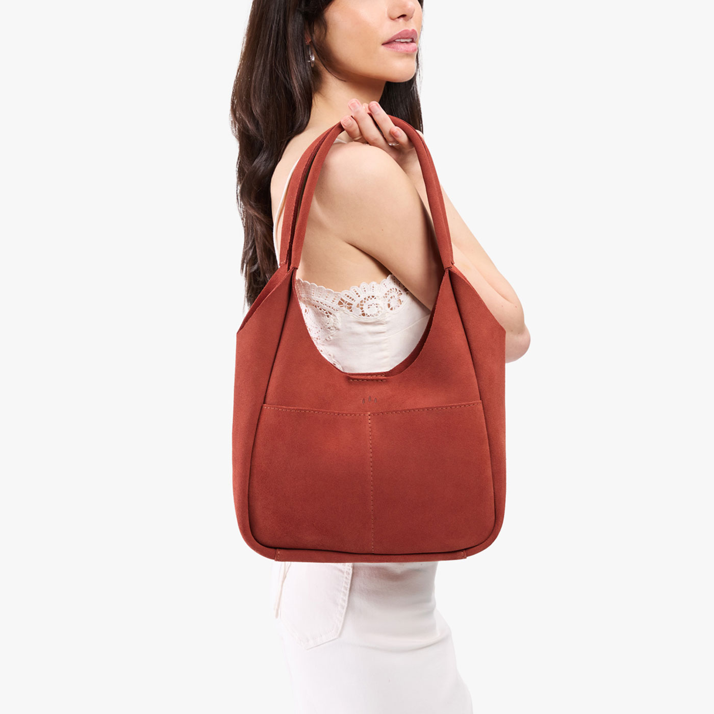 Cinnabar*Large | A model holding a u-shaped, flat-bottomed leather shoulder bag with two outside pockets