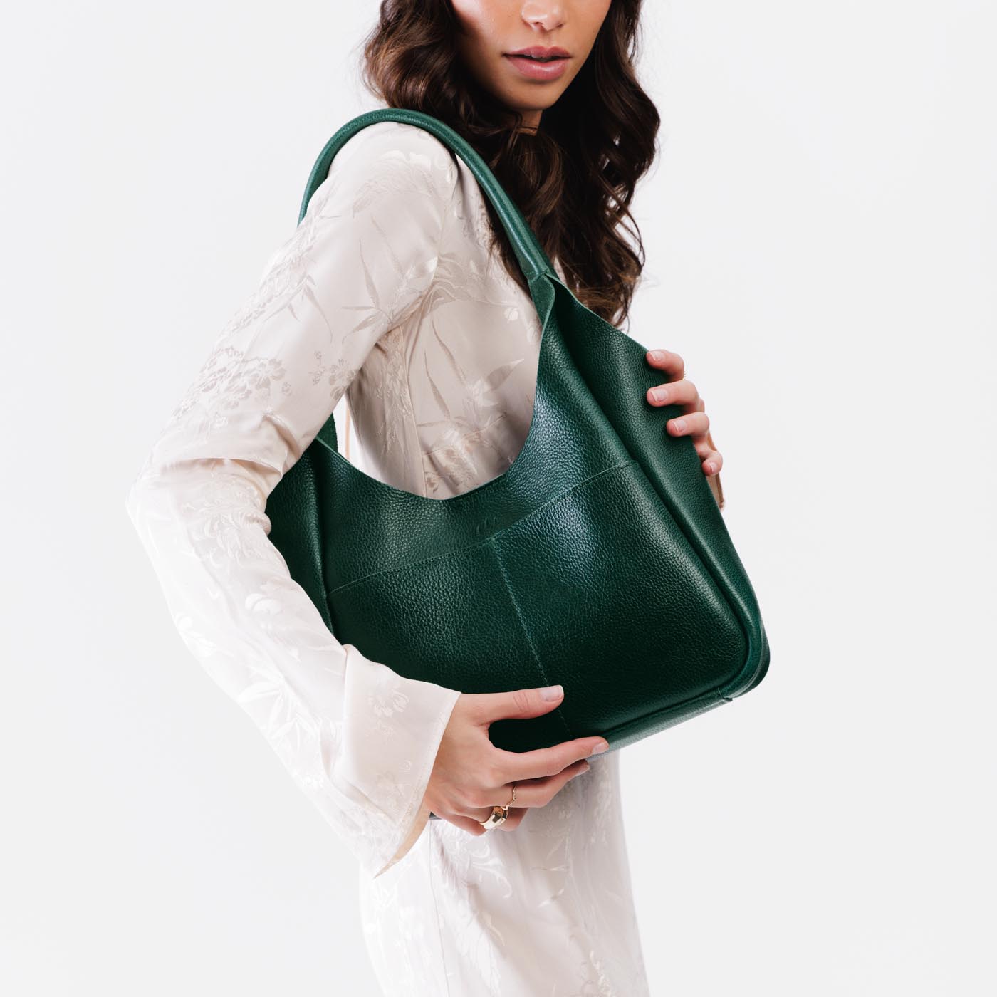 Forest Green*Large | A model holding a u-shaped, flat-bottomed leather shoulder bag with two outside pockets