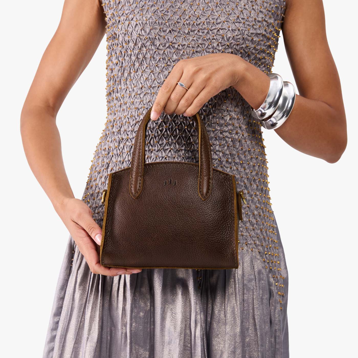 Coldbrew*Mini | Model holding small leather tote bag with handles, adjustable crossbody strap, and one back pocket