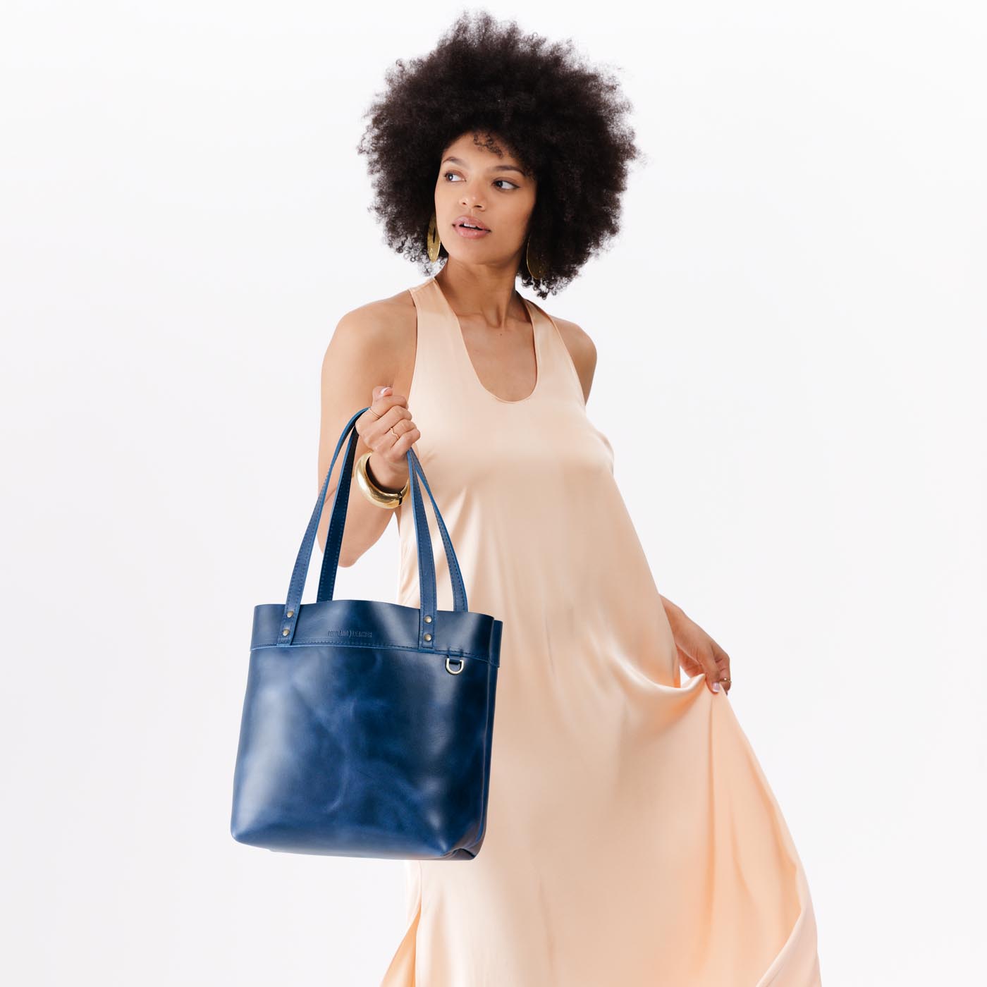 Cowboy Blue*Medium*Classic | Model holding leather tote bag with riveted straps and exterior key loop