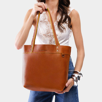 Sienna*Medium*Classic | Model holding a leather tote bag with riveted straps and exterior key loop