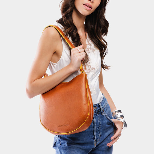 Sienna*Medium | Woman wearing rounded shoulder bag with adjustable strap on a white background