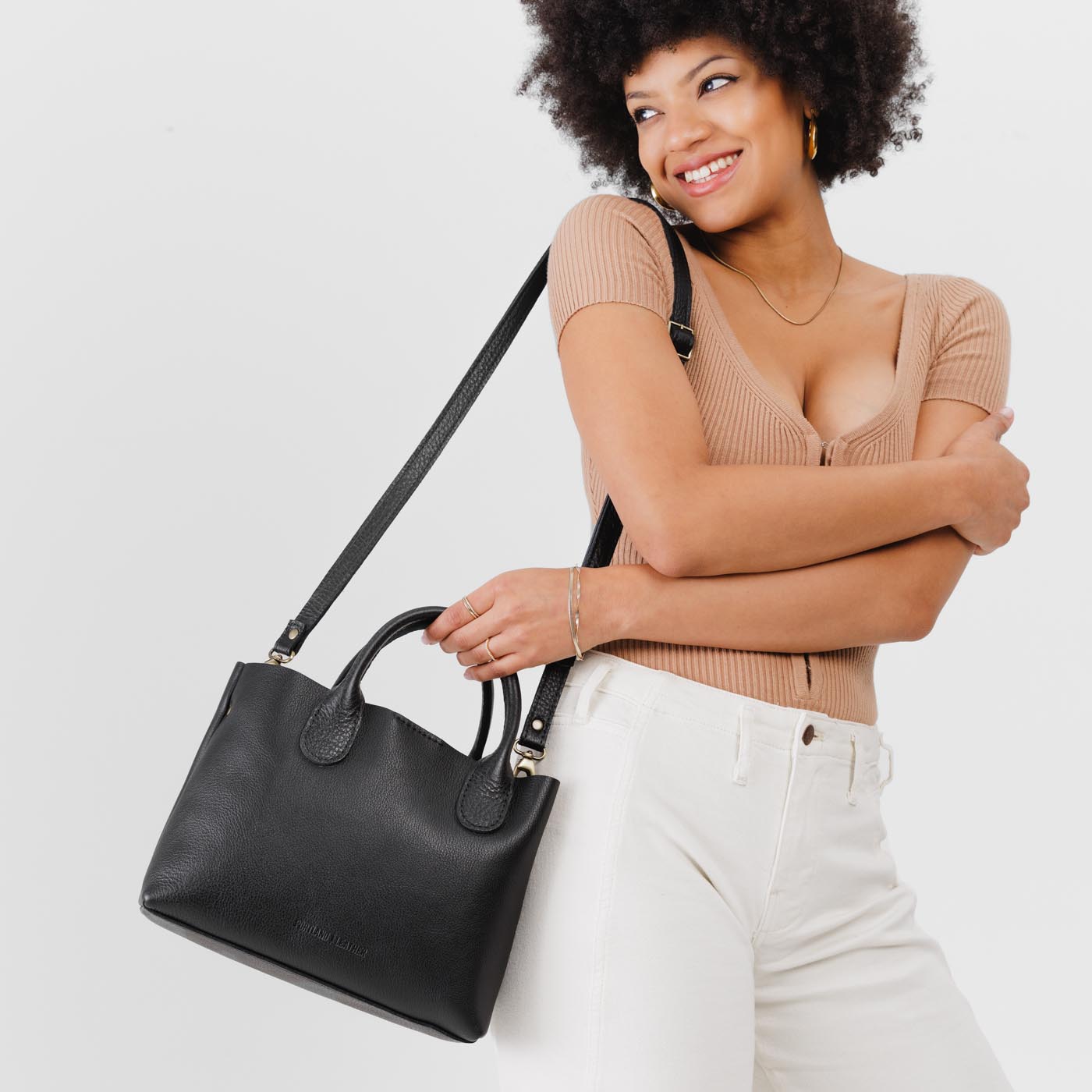 Pebbled--black*Large | Model holding mid-size tote purse with structured leather handles and crossbody strap