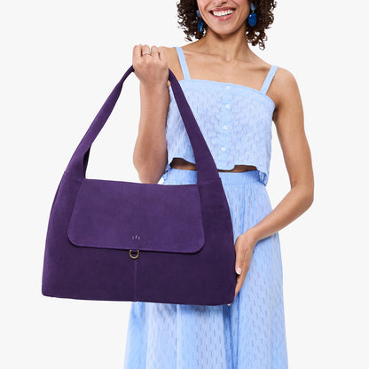 Imperial*Large | A model holding a slouchy triangle shaped shoulder bag with a flap