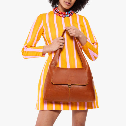 Sienna*Medium | A model holding a slouchy triangle shaped shoulder bag with a flap