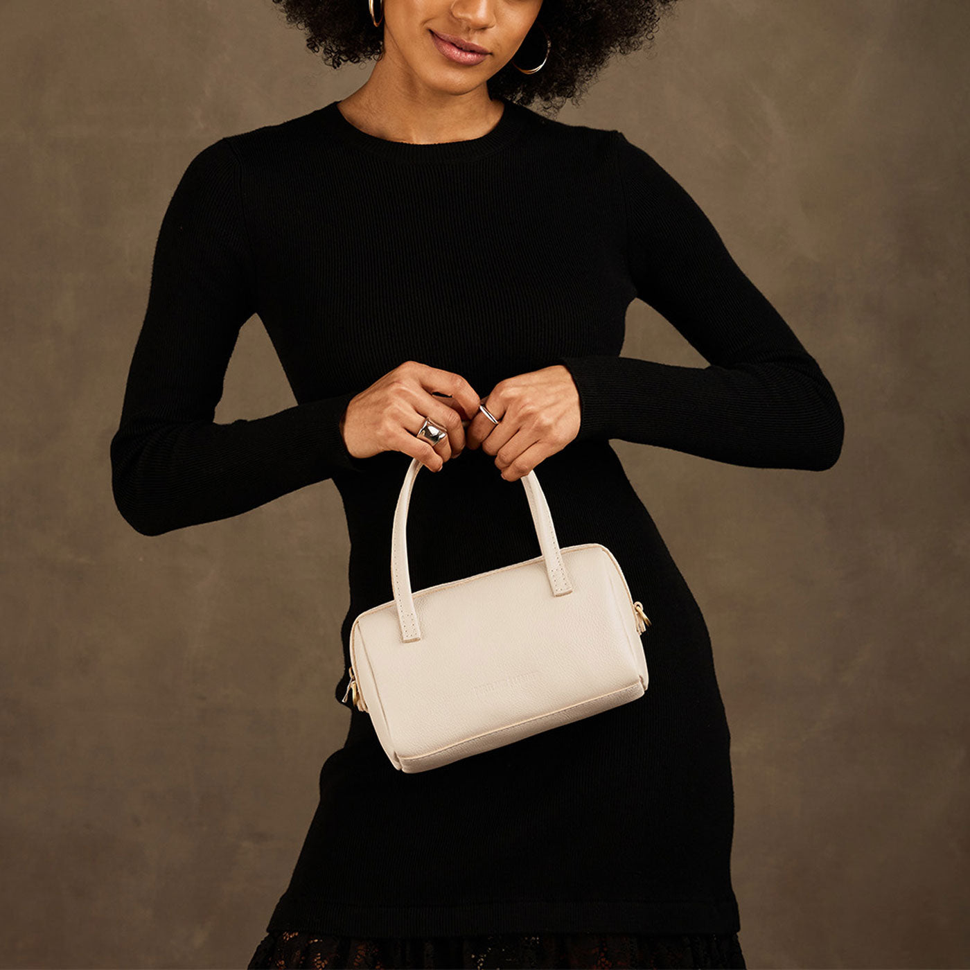 Pebbled Bone*Small | Model holding mini duffle shaped handbag with crossbody strap