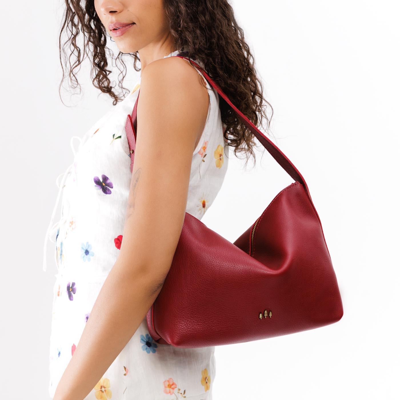 Flamenco*Large | Model wearing medium sized slouchy leather shoulder bag with zipper opening and three metal tree emblems
