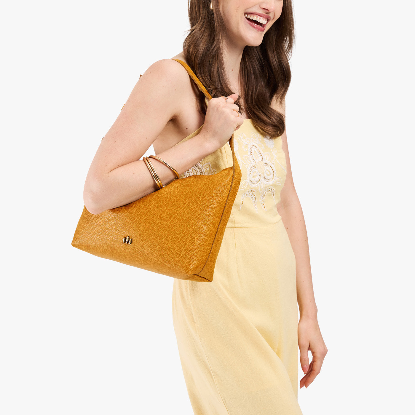 Sunshine*Large | Model holding a Slouchy Shoulder Bag that has a zipper opening and three metal tree emblems