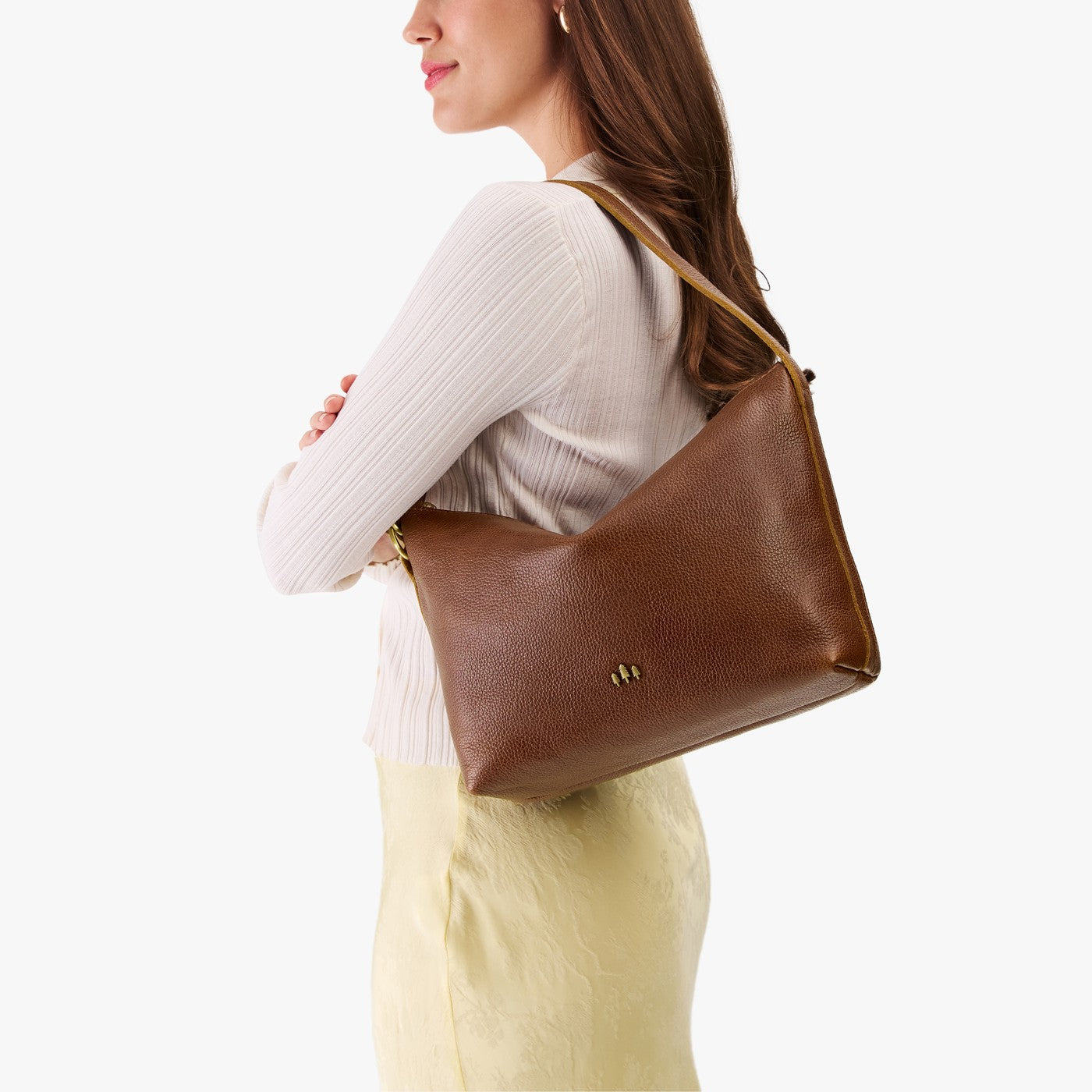 Asheville*Large | Model Wearing medium sized slouchy leather shoulder bag with zipper opening and three metal tree emblems