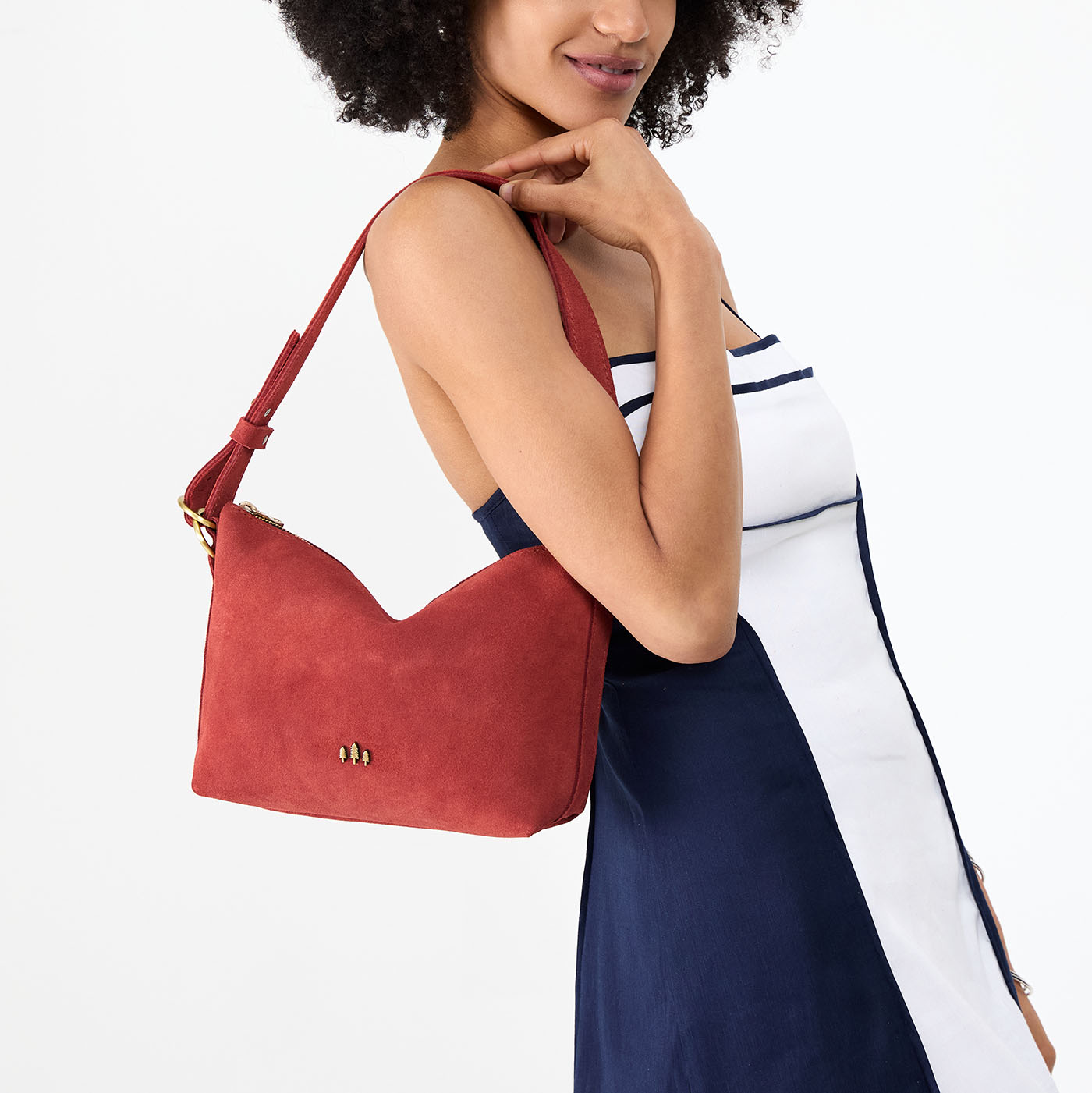 Cinnabar*Small | Model holding a Slouchy Shoulder Bag that has a zipper opening and three metal tree emblems