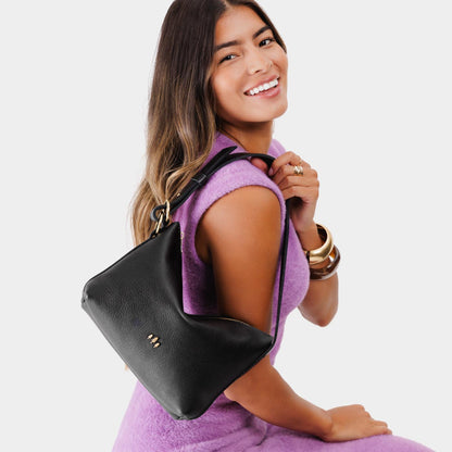 Pebbled--black*Small | Model holding petite slouchy leather shoulder bag with zipper opening and three metal tree emblems