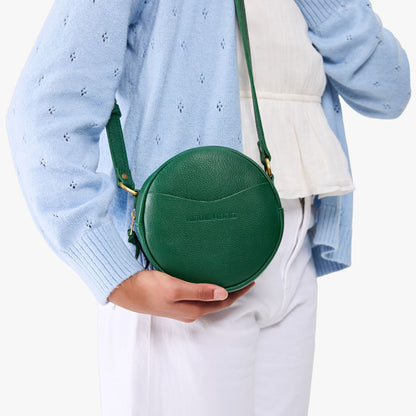Bacalar | Model wearing a circle shaped crossbody bag with top zipper and gold accents