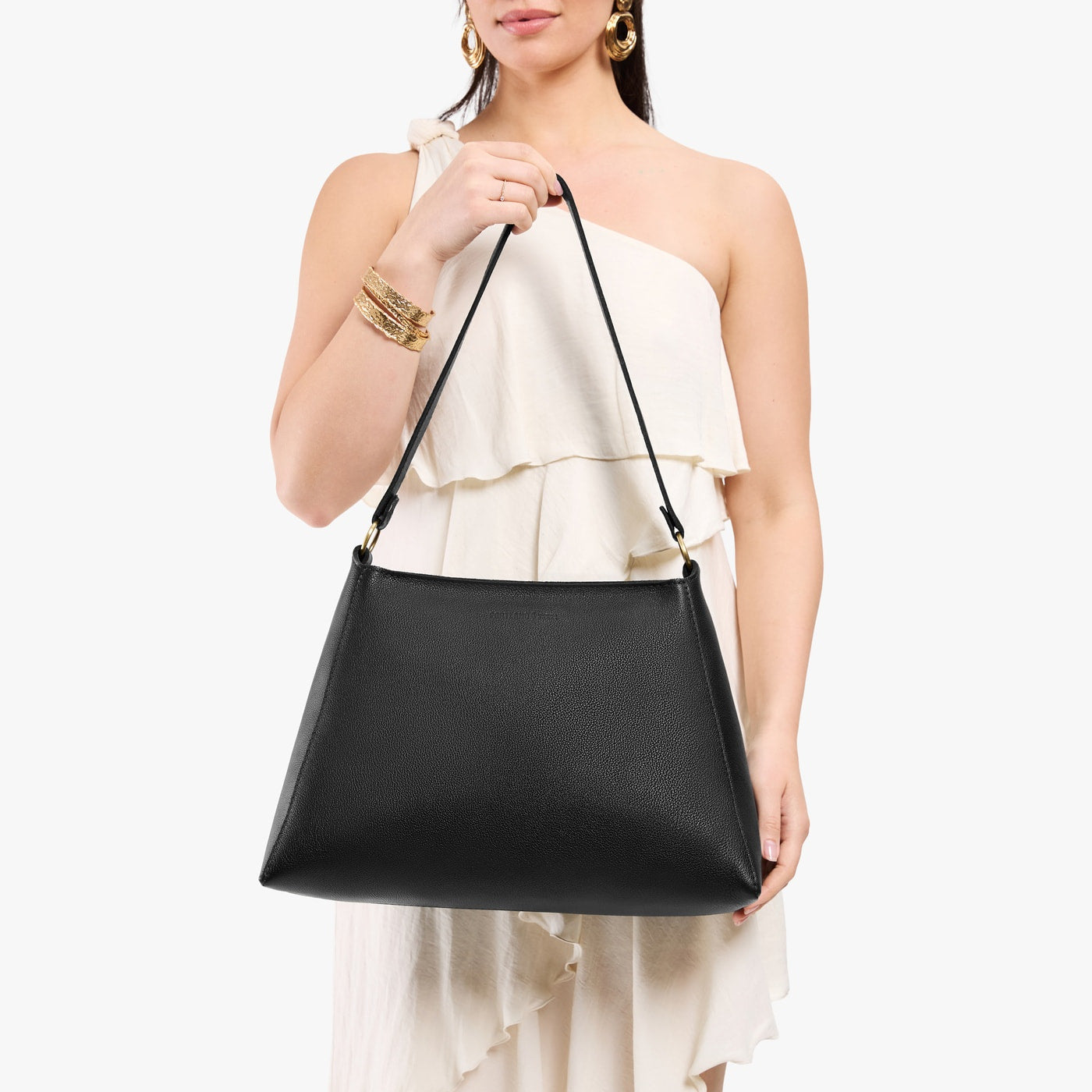 Pebbled--black*Large | Model holding large triangular shoulder bag with antiqued brass finished hardware
