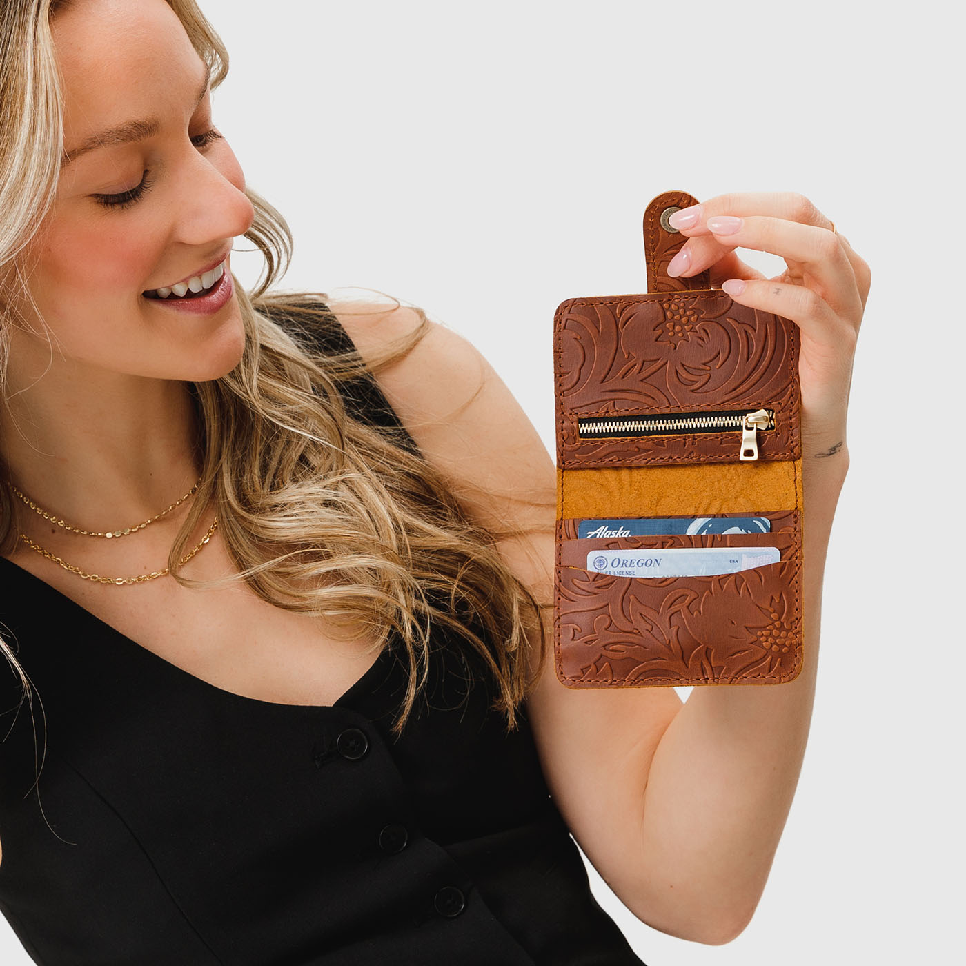 Meadow | Model holding small leather bifold wallet with snap opened