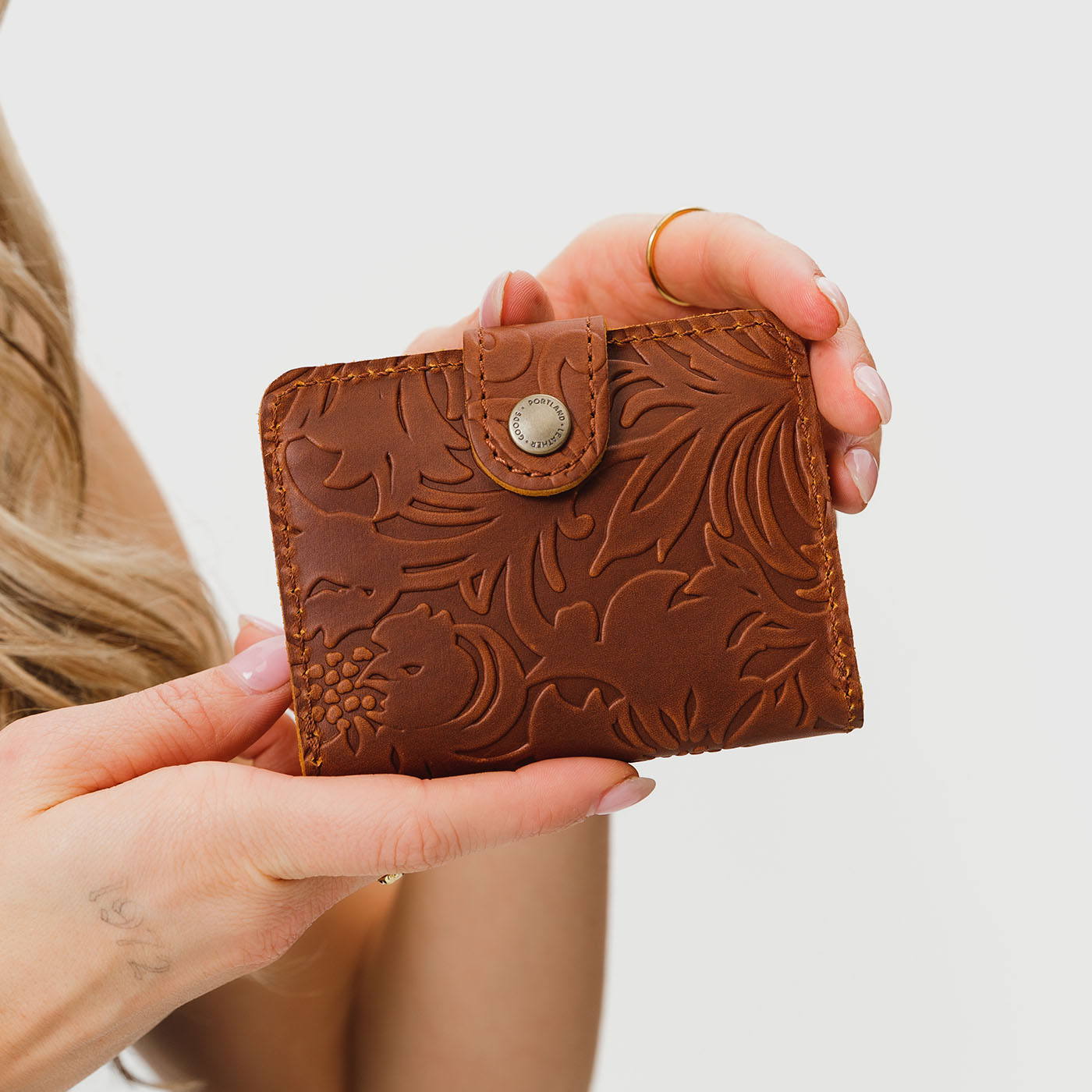Meadow | Model holding small leather bifold wallet with snap closed